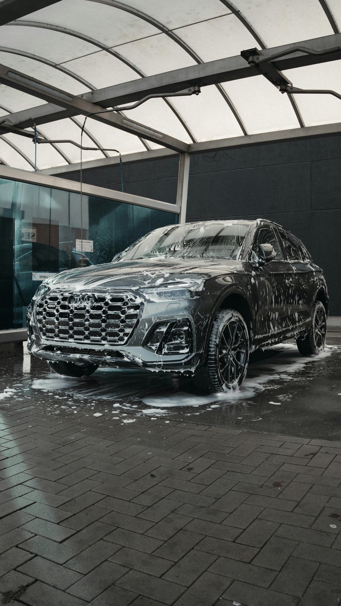 A dark suv covered in soap at a car wash.